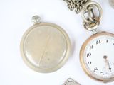 a silver pocket watch and a silver pocket watch on a white surface