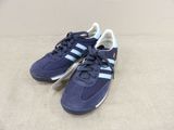 une paire de baskets Adidas bleues posées sur une surface beige