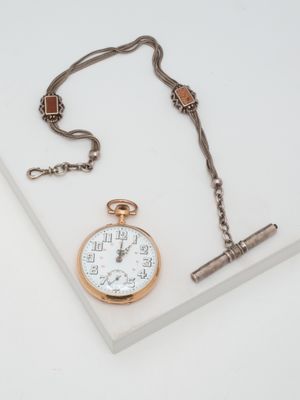 a pocket watch and a chain on a white surface