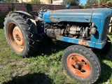 un tracteur bleu qui est garé dans l'herbe