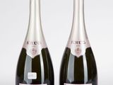 deux bouteilles de champagne posées l'une à côté de l'autre sur une surface blanche