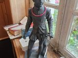 une statue représentant un garçon debout sur un bureau près d'une fenêtre