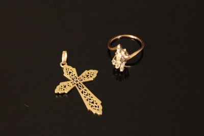 two gold rings and a cross on a black surface