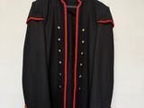 une veste noire aux bordures rouges accrochée à un mur blanc