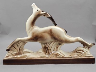 statue d'un cerf posé sur un rocher, avec un oiseau sur le dos
