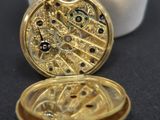 an image of a gold pocket watch sitting on top of a white box