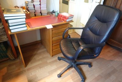 une chaise de bureau noire placée devant un bureau sur lequel sont posés des livres