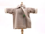 un ours en peluche vêtu d'un manteau, posé sur un mannequin