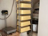 a rack with several trays of cheese on it in a kitchen