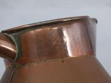a large copper pitcher with a handle on a table