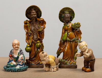 trois figurines représentant des personnes d'origine asiatique, posées sur une table