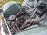 an old green car with an engine in the trunk