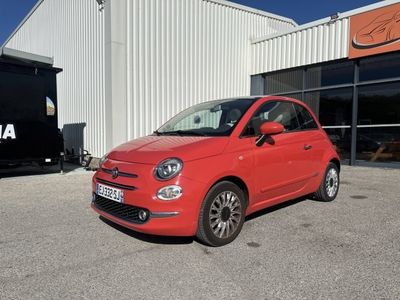 La petite voiture rouge est garée devant un immeuble.