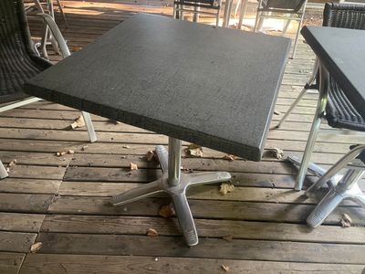 une table et des chaises noires sur une terrasse en bois