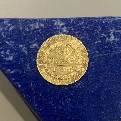 une image représentant une pièce d'or posée sur un bloc de marbre bleu