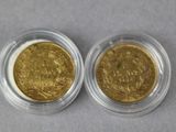 two gold coins in a clear plastic container on a gray surface