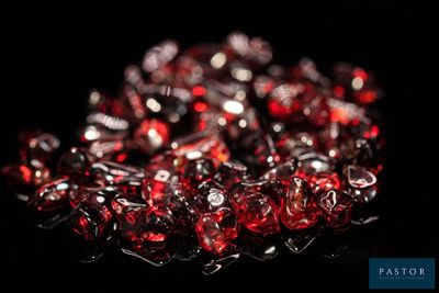 un gros plan sur un bouquet de perles de verre rouges posées sur une surface noire