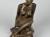l'image d'une statue de bronze représentant une femme assise sur un rocher