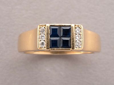 a close up of a gold ring with a sapphire and diamonds