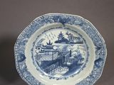 two blue and white plates with designs on them sitting on a table