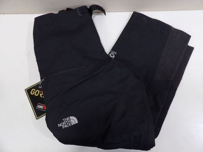 un gros plan sur un pantalon noir posé sur une surface blanche