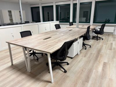une longue table avec des chaises et un ordinateur portable posé dessus, dans un bureau