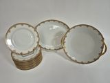 quatre assiettes en porcelaine blanche et dorée, ornées de bordures dorées