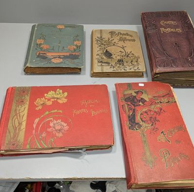 Plusieurs vieux livres sont posés sur une table blanche, à côté d'une paire de ciseaux