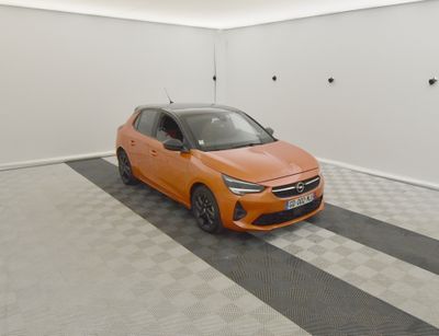 Une voiture orange est garée dans un garage dont le sol est en damier.