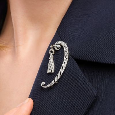 a close up of a woman ' s hand holding a silver broochet