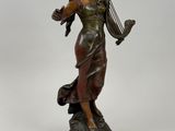 a bronze statue of a woman holding a harp on a pedestal