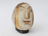 a ceramic sculpture of a woman ' s face on a stand