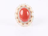 a close up of a ring with a red stone surrounded by white stones