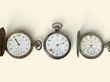 trois types différents de montres de poche sont présentés sur une surface blanche