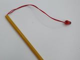 a yellow pencil with a red string attached to it sitting on a white surface