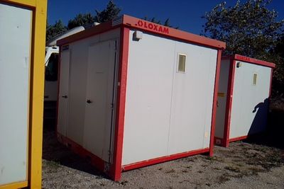 three portable toilets sitting in the dirt next to each other