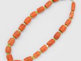 un collier orange orné de perles vertes et muni d'un fermoir doré