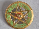 un pentagramme doré et vert surmonté d'une étoile