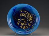 a blue bowl with gold flakes in it on a stand