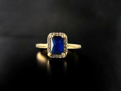 a gold ring with a blue sapphire stone surrounded by diamonds