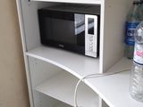 a microwave on a shelf with a bottle of water on top of it