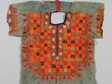 une chemise brodée orange et verte, avec des motifs géométriques sur fond blanc