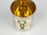 a silver cup with a green snake on the side of it