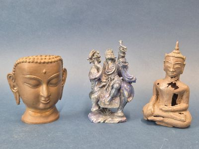 trois petites statues de bouddhas assis les uns à côté des autres sur une surface bleue