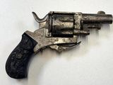 un pistolet posé sur une surface blanche, avec une crosse noire