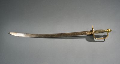 a gold colored sword with a gold handle on a gray surface
