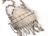 an old silver metal purse with chains hanging from it ' s sides