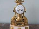 a gold clock sitting on top of a marble table