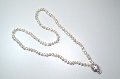 a white pearl necklace with a silver clasp on a white table