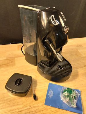 une cafetière noire posée sur une table à côté d'une télécommande